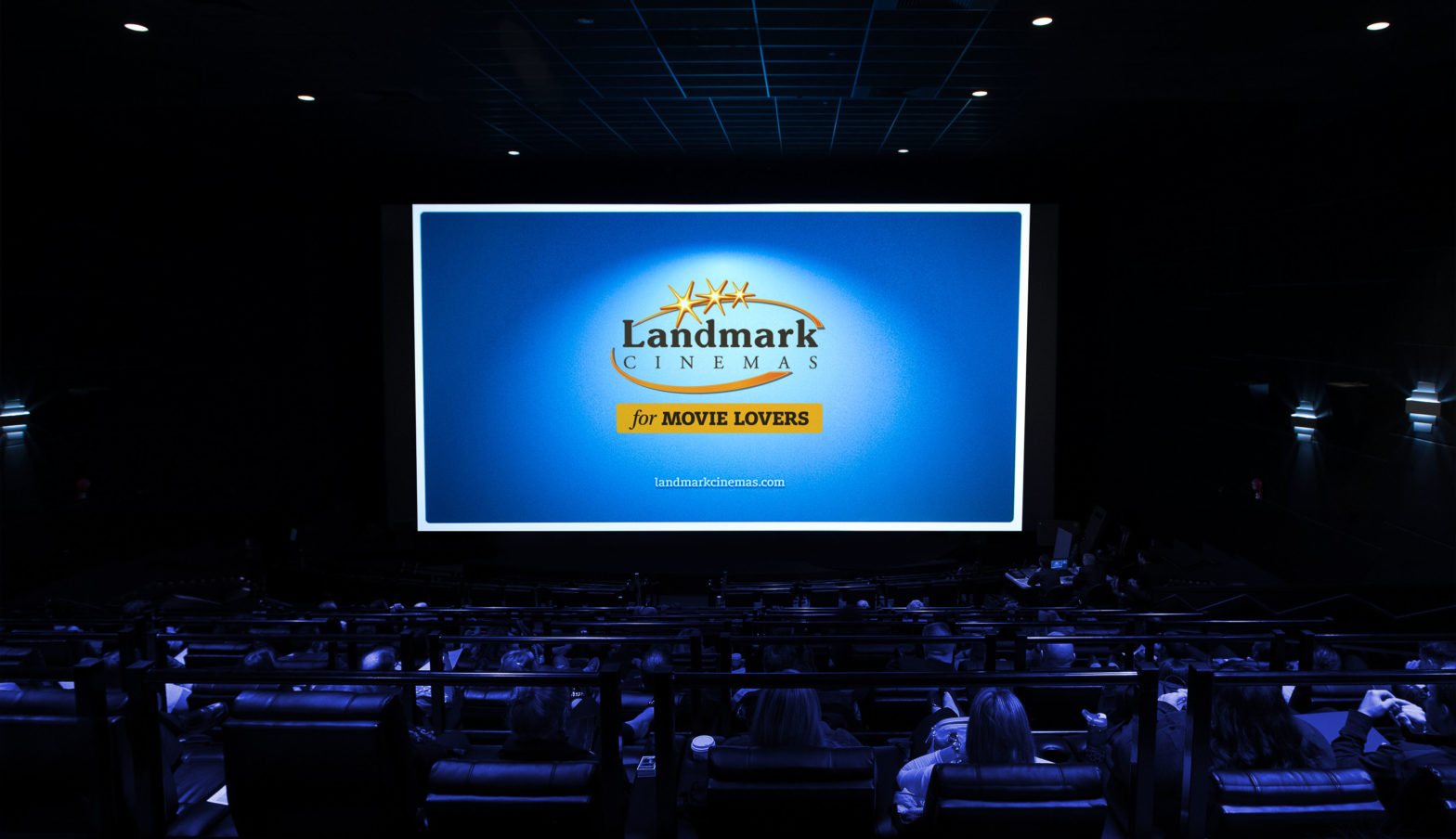 An audience sitting in a Landmark Cinemas cinema, Landmark's logo displayed on the big screen.