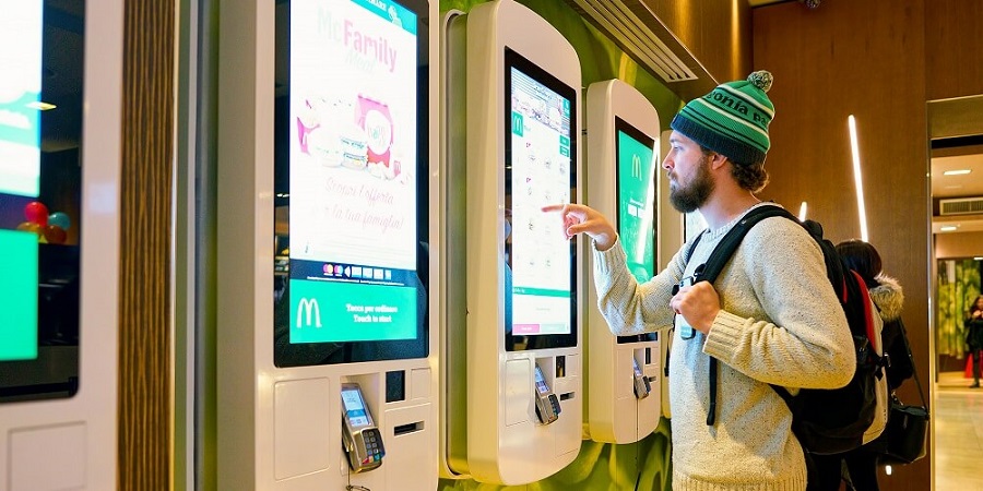 A man at a McDonald's self-serve touchscreen