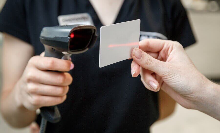 A person holding a laser scanner and scanning a loyalty card held by a customer.